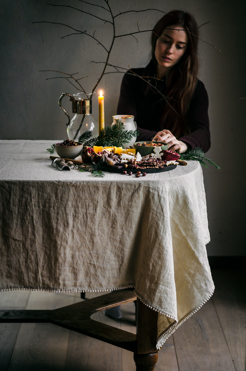 Woman sitting behind table set with holiday spread.